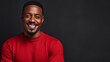 © ALA - Strong black smiling African man in a red sweater on a dark background on the day of the Black Friday sale.