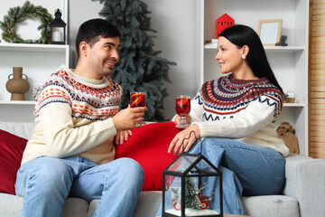 Sticker - Young couple with glasses of mulled wine at home on Christmas eve