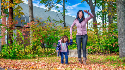 Poster - A happy young girl jumping with her mother in the forest, autumn foliage season