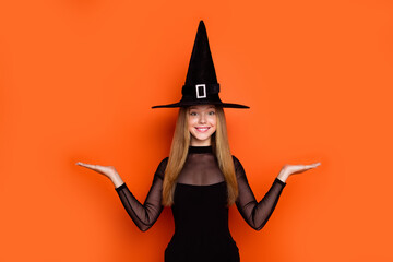 Sticker - Portrait of charming teen schoolgirl wizard costume arms hold empty space vs scales isolated on orange color background