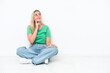 © luismolinero - Young caucasian woman sitting on the floor isolated on white background thinking an idea while looking up