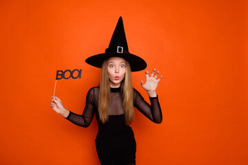 Canvas Print - Photo portrait of pretty blonde teenager girl hold boo sign scratch hand dressed black halloween outfit isolated on orange color background