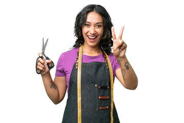 Wall Mural - Young seamstress argentinian woman over isolated background smiling and showing victory sign