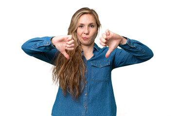 Wall Mural - Young blonde woman over isolated background showing thumb down with two hands