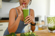 © Prathankarnpap - Shot of young woman in sportswear drinking green vegetables smoothie after her morning workout
