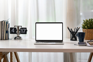 Wall Mural - Front view laptop computer with blank display, books, coffee cup, stationery and potted plant on white table