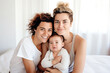 © Jasmina - Portrait of happy female Gay couple with baby at home. Concept of lgbt people, lesbian marriage and adoption, homosexual family