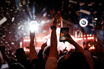 Wall Mural - Crowd of people having fun while watching confetti fireworks at music festival.