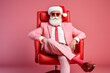 Stylish Santa Claus with glasses and red suit sitting like a Boss in the armchair. Creative New Year and xmas holiday pastel green background banner. 