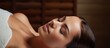 Young woman being pampered with a massage in a tranquil spa Brunette girl lies with closed eyes on a massage bed experiencing a spa treatment for beauty skin care and wellbeing With copyspac