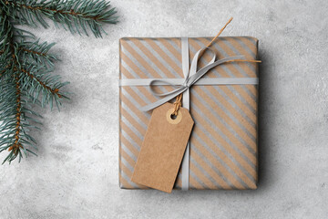 Wall Mural - Christmas gift box with craft paper gift tag or label and fir tree branch on grey concrete background, winter holidays concept