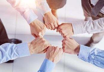 Closeup view businesspeople standing in circle fists bumping showing unity