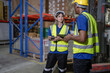 © Nassorn - Distribution warehouse manager using tablet to check stock on storage shelf. Multiethnic man worker and colleague working together at storehouse discussing inventory as order. Diversity people talking