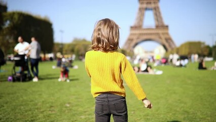 Wall Mural - Adorable happy preschooler girl having fun near the Eiffel tower in Paris, France