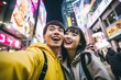 Happy asian couple taking selfie with mobile phone in the city