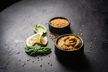 Poster - Fresh homemade organic dijon mustard in a bowl on black background, close up