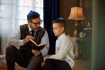 Jewish father and his son studying Hebrew bible together at home.