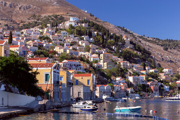 Wall Mural - Colorful traditional multi-colored houses on the shore of the bay on Symi island.