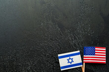 USA Israel Flags. Two Small American And Israeli Flags Lie On Black Old Texture Background Opposite Each Other Conveys Partnership Between Two States Through Main Symbols Of These Countries. Mock Up.