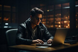 Fototapeta Konie - A handsome brunette man wearing sunglasses and a black leather jacket is working on a laptop