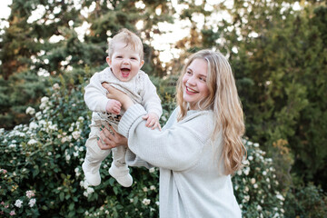 Happy smiling mother holding baby over nature background closeup. Motherhood.