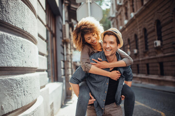 Wall Mural - Young mixed couple embracing each other while having a stroll in the city