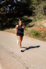 Young happy healthy woman doing exercise walking and run on country road in Ibiza in the morning background, concept of health and lifestyle.