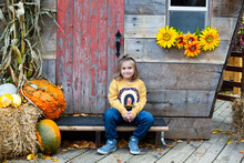 
Adorable Smiling Little Blond Girl Sitting On The Steps Of A Hut Decorated With Pumpkins For Halloween, Quebec City, Quebec, Canada