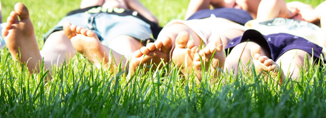 Wall Mural - Children's legs on green grass. Selective focus.