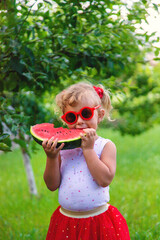 Poster - A child eats a watermelon in the park. Selective focus.