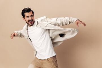 Wall Mural - Stylish man smile runs and jumps on a beige background in a white t-shirt and business jacket, flying clothes hero, fashionable clothing style, copy space, space for text