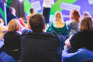 Audience at the conference hall listen to lecturer, people listen to speaker on a bean bags stage at master-class, college students in the auditorium, participants of corporate business seminar