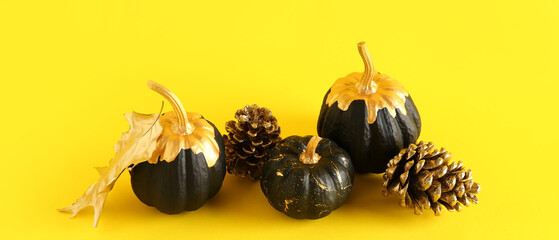 Black painted pumpkins, cones and autumn leaf on yellow background. Halloween celebration