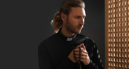 Portrait of male priest in confession booth