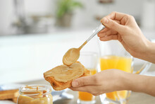 Young Woman Spreading Nut Butter Onto Toast In Kitchen, Closeup