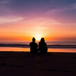 © Kholoud - silhouette of a couple sitting on beach in the sand watching a beautiful sunset.