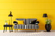 Retro style sitting area white painted floorboards black and white striped sofa large potted floor plant floor lamps and occasional table set against a yellow panelled wall interior design