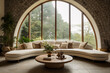 Contemporary country sitting room with large half round sofa and cushions with solid wood round coffee table against a large arched window set in natural brickwork tiled floor interior room design