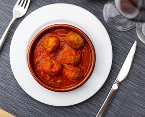 Canvas Print - Multiple meatballs in tomato sauce served in a bowl with other table appointments