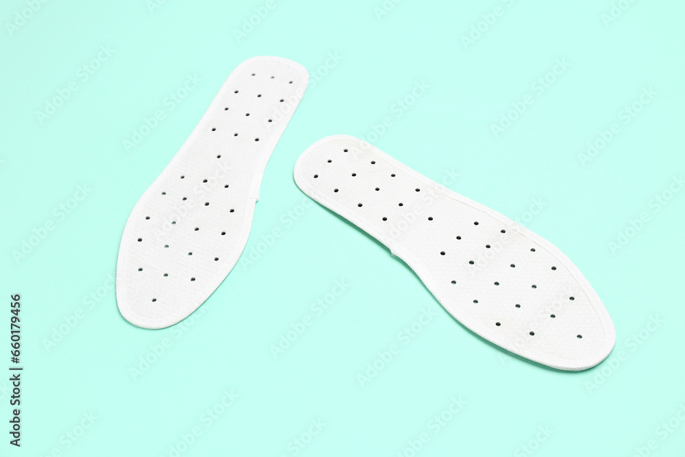 Pair of white orthopedic insoles on color background