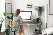 © Pixel-Shot - Young woman working with computer at table in office