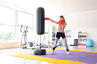 Young woman training with punching bag in gym. Concept of self defense
