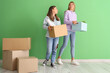 © Pixel-Shot - Female students with moving boxes near green wall in dorm room