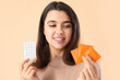 © Pixel-Shot - Young woman with condoms and birth control pills on beige background