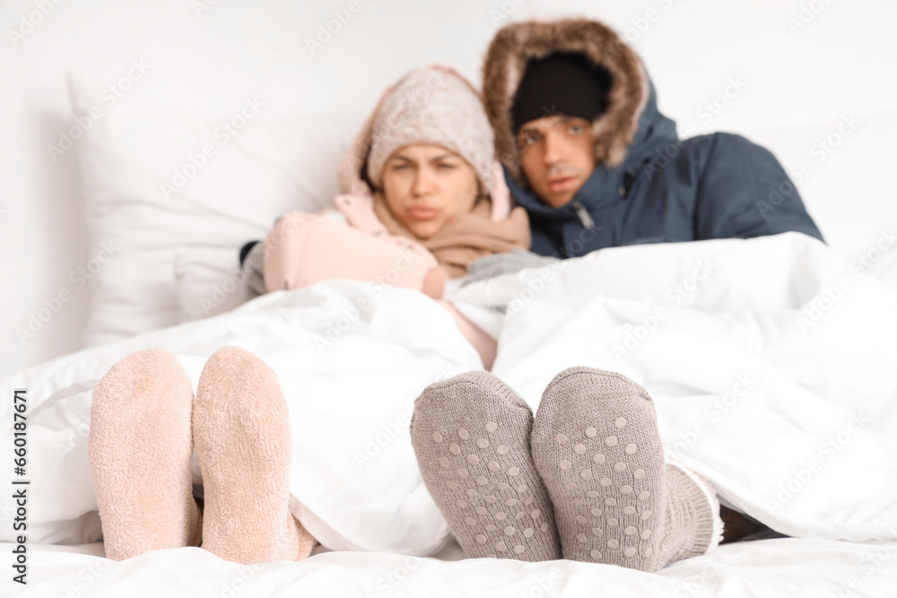 Frozen young couple with warm socks lying in bedroom, closeup