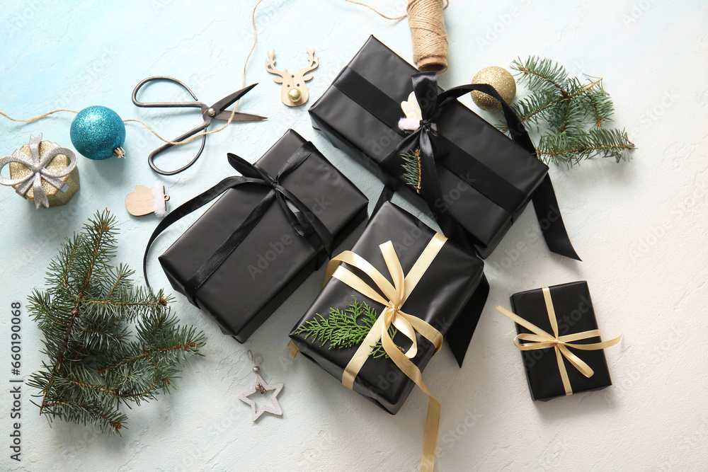 Black gift boxes with Christmas tree branches and beautiful decorations on light blue background