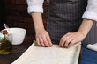 © New Africa - Woman making delicious baklava at wooden table, closeup