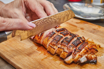 Wall Mural - Chef slices the finished duck breast after frying on wooden board for serving