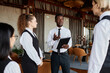 © Seventyfour - Portrait of young Black man talking to servers wearing classic uniforms during staff meeting in restaurant