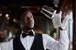 Portrait of Black young man as elegant waiter polishing glasses in luxury restaurant, copy space